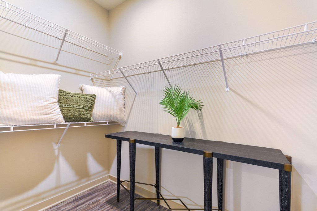 a study area with a table and pillows and a shelf with a plant