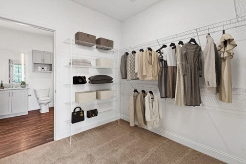 A white closet with a variety of clothes hanging on shelves and racks.