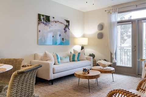 A living room with a white couch, a painting on the wall, and a rug on the floor.
