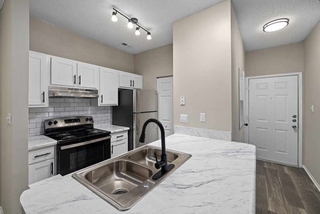 a kitchen with white cabinets and black appliances and a sink