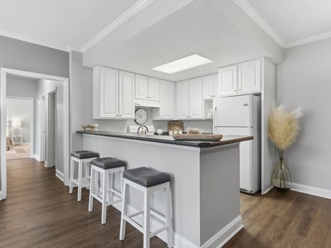 A kitchen with white cabinets and a grey island.
