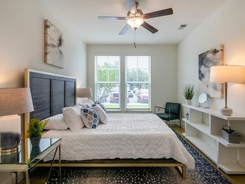 A bedroom with a bed, a chair, and a ceiling fan.