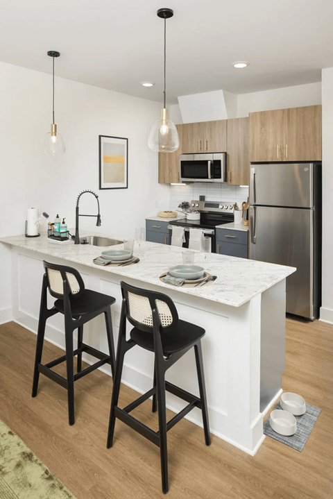 A kitchen with a white countertop and black barstools at Boardwalk at Research Park apartments in Huntsville, AL.