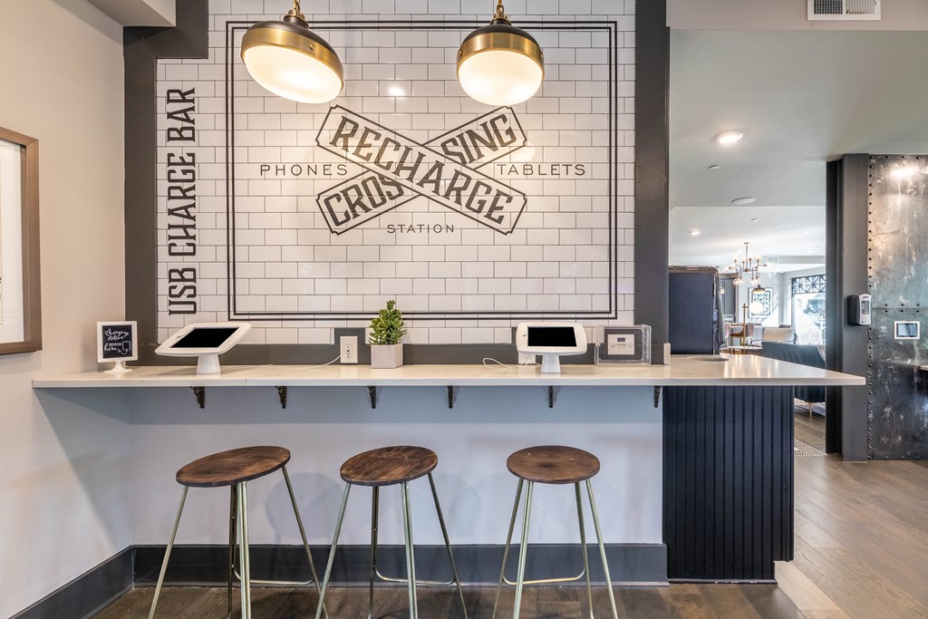 a bar with three stools in front of a white brick wall with a sign