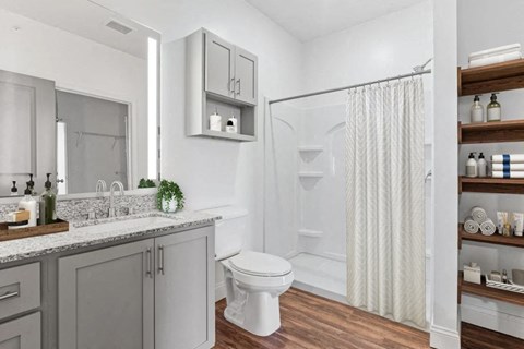 A white toilet sits in a bathroom with a white shower curtain.