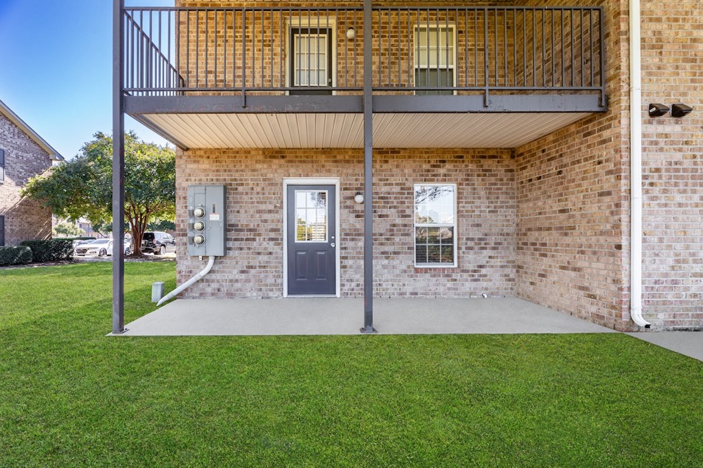 A balcony with a metal railing overlooks a green lawn.