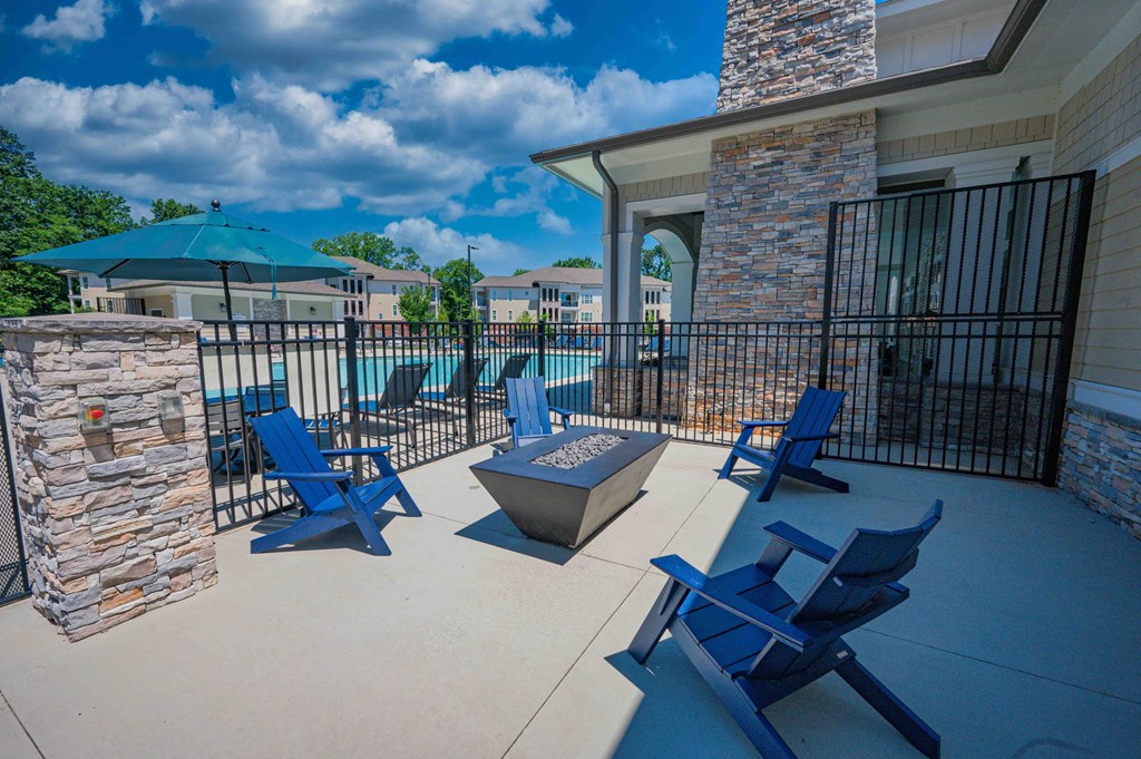 the patio has a fire pit with blue chairs and umbrellas