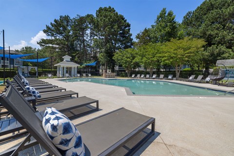 a swimming pool with lounge chairs next to a resort style pool