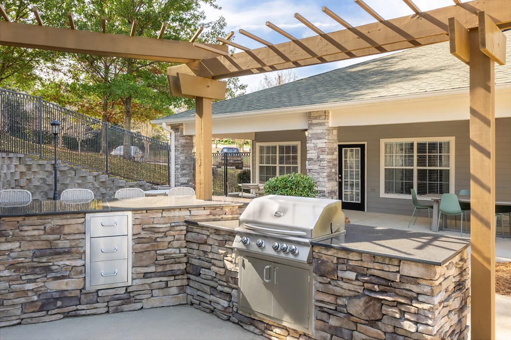 an outdoor kitchen with a grill and a pergola