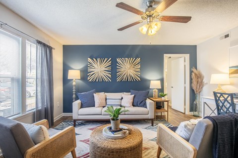a living room with a couch and chairs and a ceiling fan