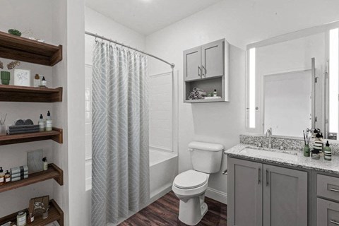 A white toilet sits in a bathroom next to a shower curtain.