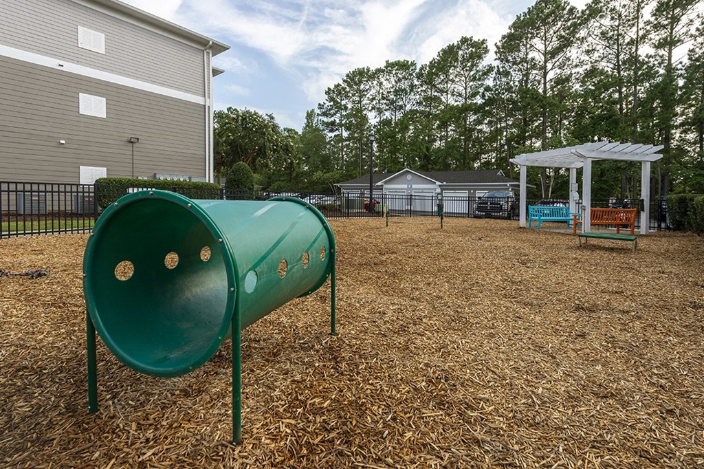 a green mailbox in a park with a playground and a pavilion