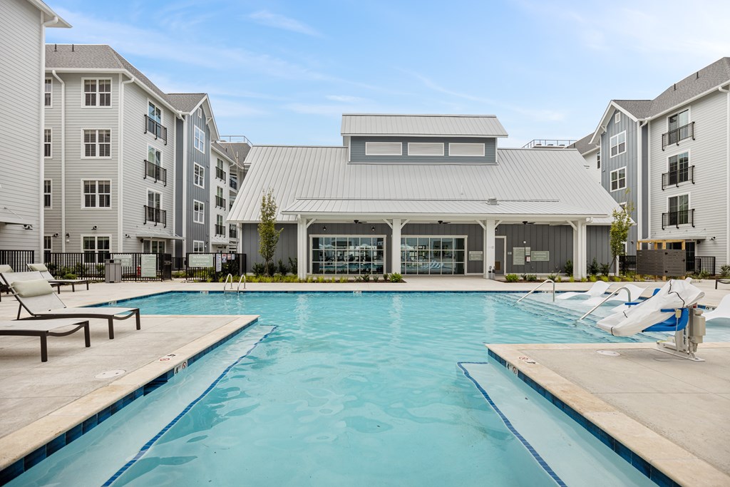 Large Swimming Pool with Lounge Chairs and the Clubhouse Behind it.