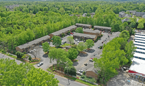 an aerial view of a parking lot with buildings and trees