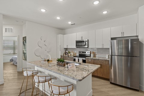 a kitchen with a marble counter top and a stainless steel refrigerator