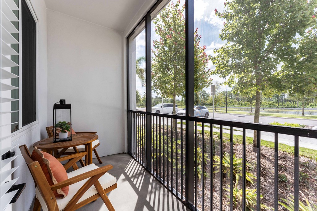 A balcony with a wooden table and chairs overlooking a green landscape.