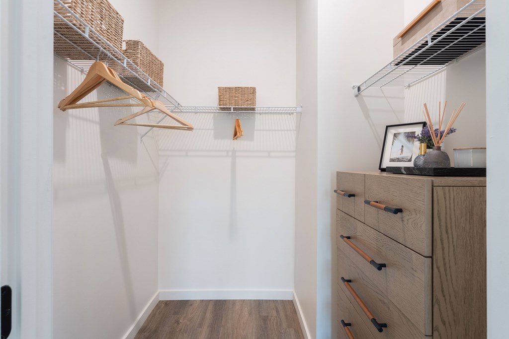 A large closet with a wooden dresser and shelves.