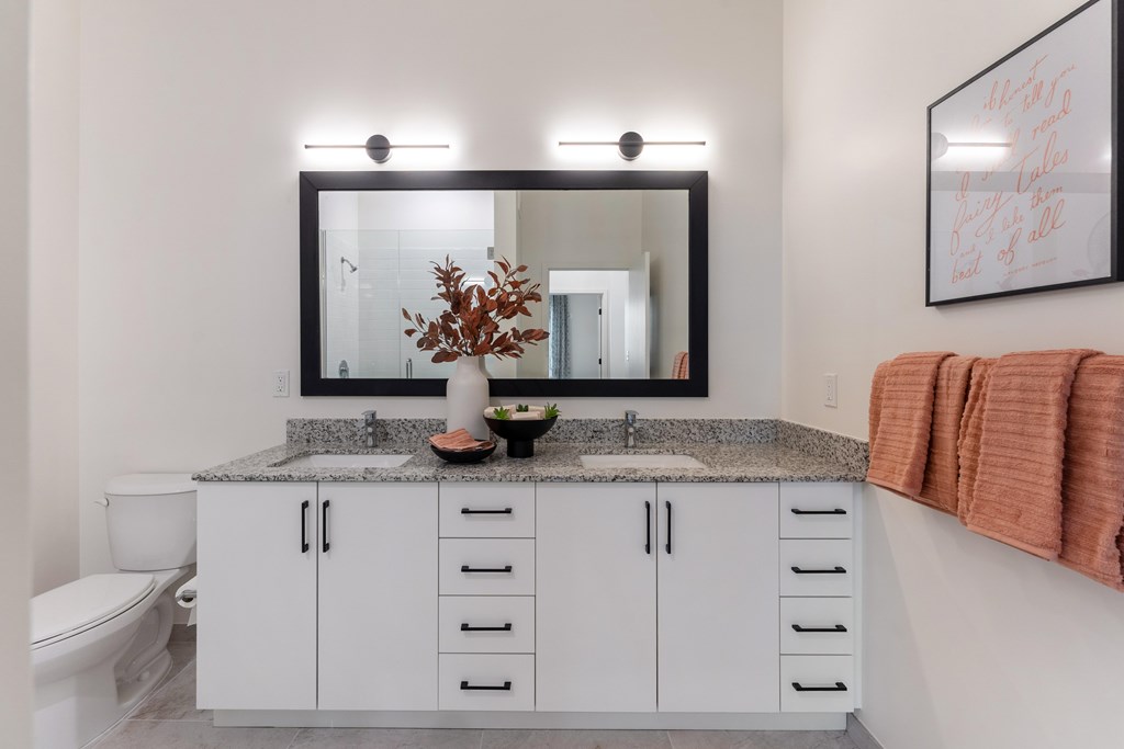 A bathroom with a granite counter top and a large mirror.