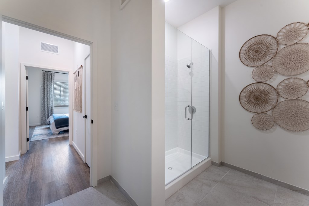 A bathroom with a glass shower door and a wall hanging.