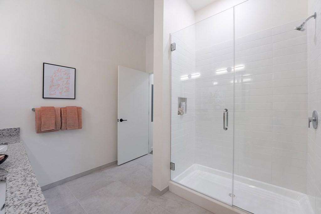 A bathroom with a walk-in shower and a towel hanging on the wall.
