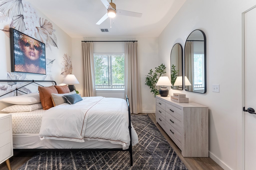 A bedroom with a bed, dresser, and mirror.