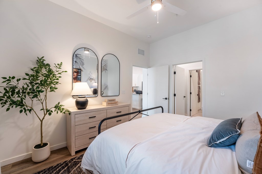 A bedroom with a bed, dresser, and mirror.