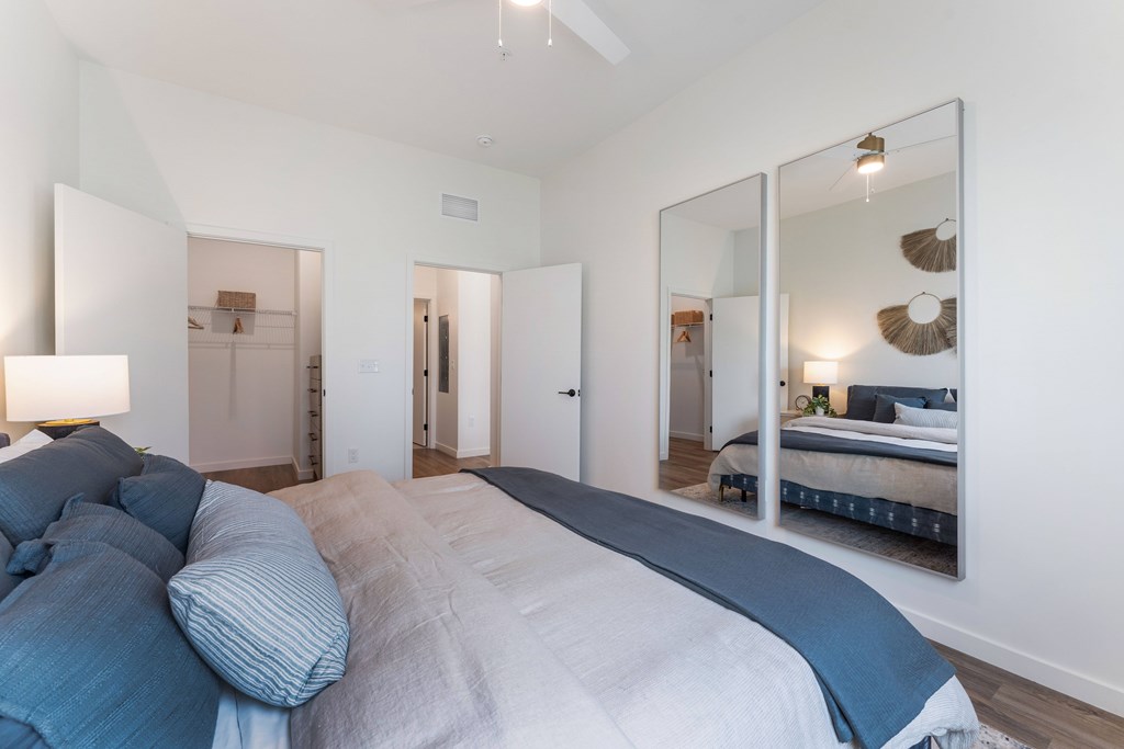 A bedroom with a large bed and a mirror on the wall.