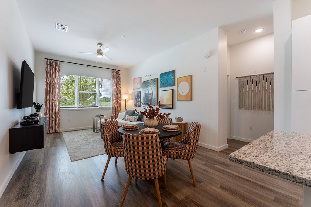 A dining room with a table set for four and a television on the wall.