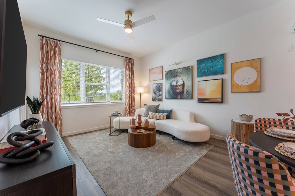 A living room with a white couch, a coffee table, and a ceiling fan.