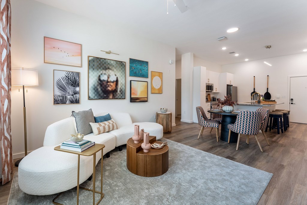 A living room with a white sofa, a grey rug, and a wooden coffee table.