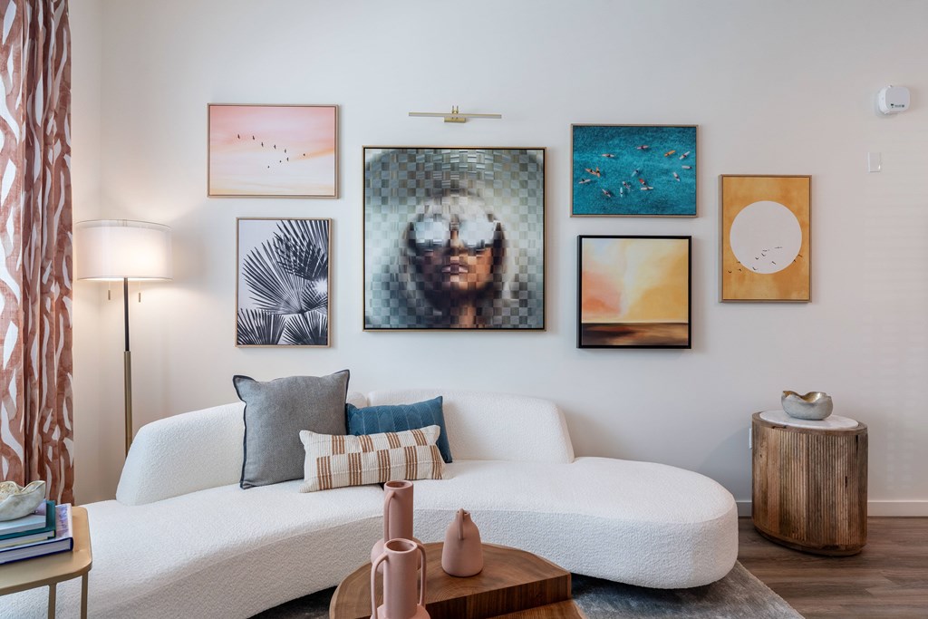 A living room with a white couch, a wooden table, and a painting on the wall.
