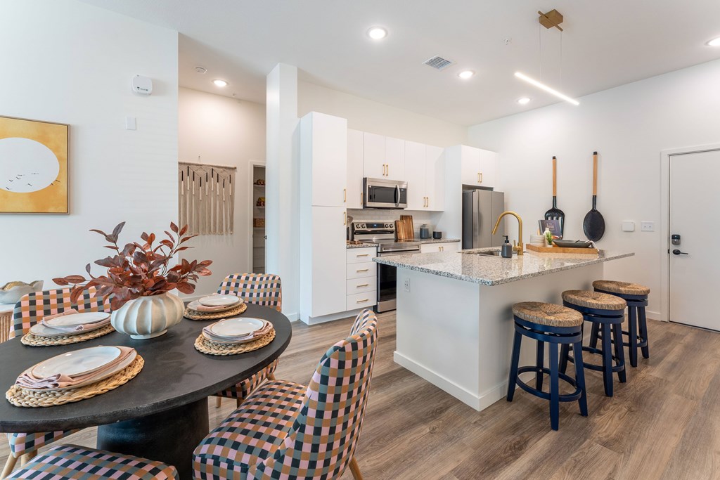A kitchen with a bar and chairs around a table.