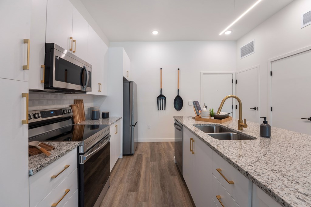 A kitchen with white cabinets and a granite countertop.