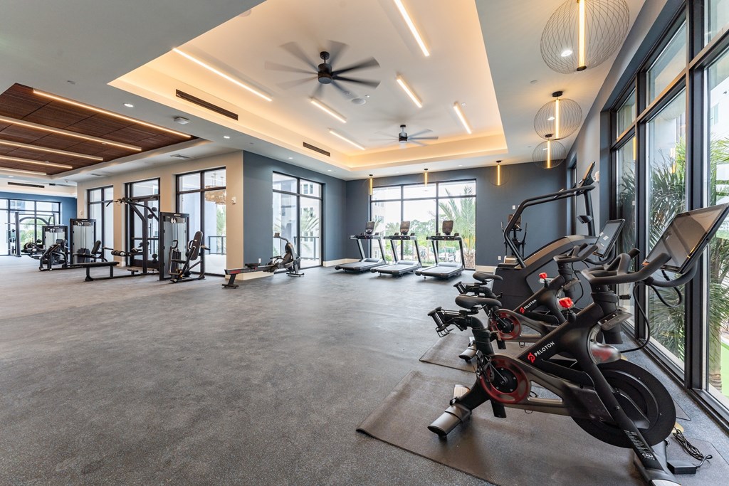A spacious gym with a variety of exercise equipment and large windows.