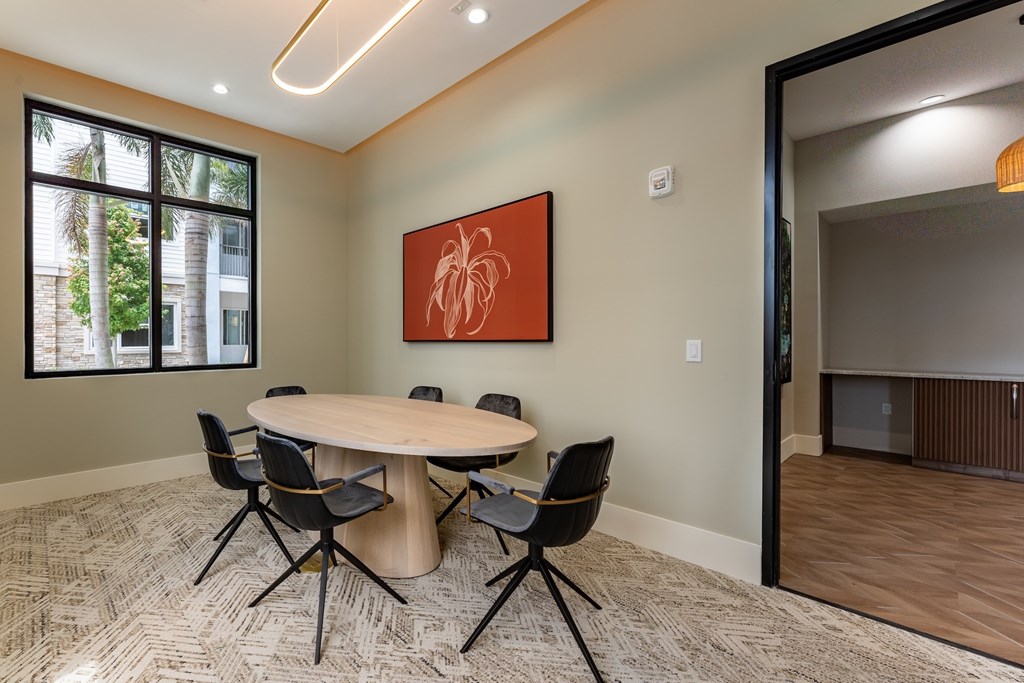 A conference room with a table, chairs, and a painting on the wall.