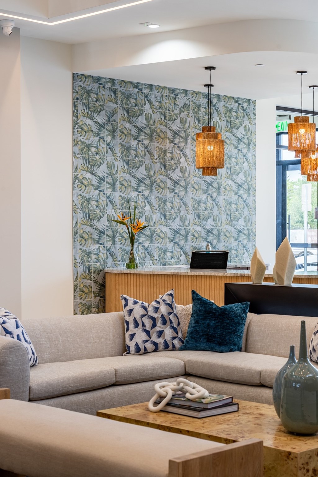A living room with a grey couch, a wooden coffee table, and a wallpapered wall.