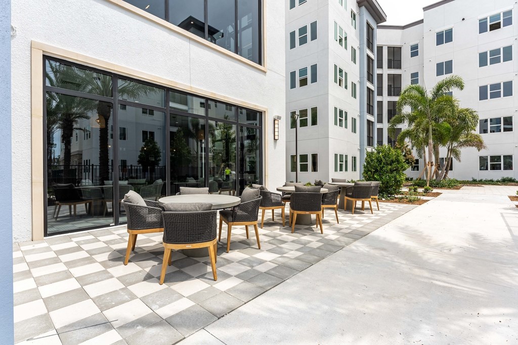 A patio with a table and chairs is in front of a white building.