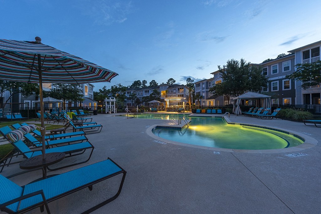 a large pool with chairs and umbrellas at night