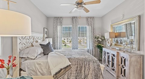 A bedroom with a large bed and a ceiling fan.