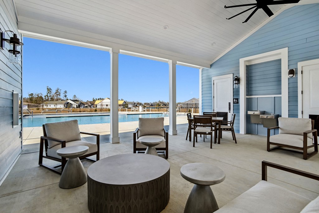 A patio with a pool and chairs and tables at 15 at Heron apartments in Longs, SC.