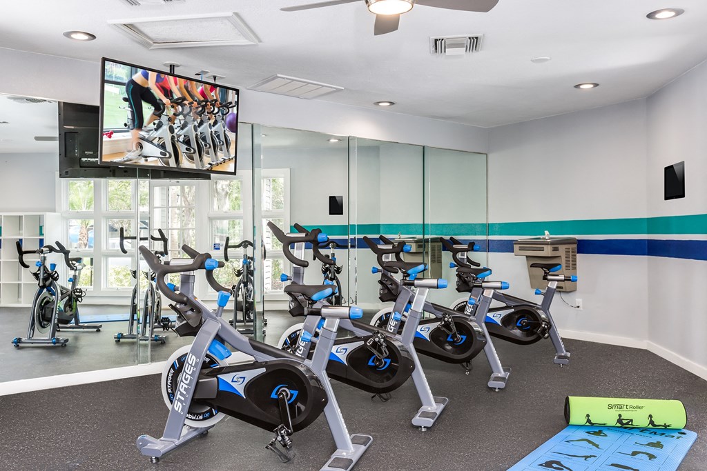 a fitness room with exercise bikes and a large screen tv