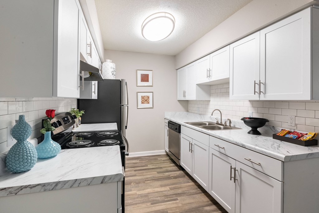 an open kitchen with white cabinets and marble counter tops and a stove and refrigerator