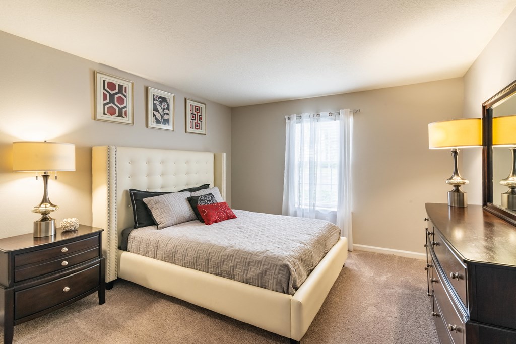 a bedroom with a bed and a dresser and a window