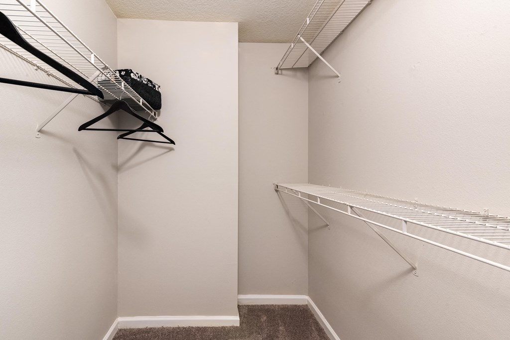 a spacious closet with white walls and two racks on the wall