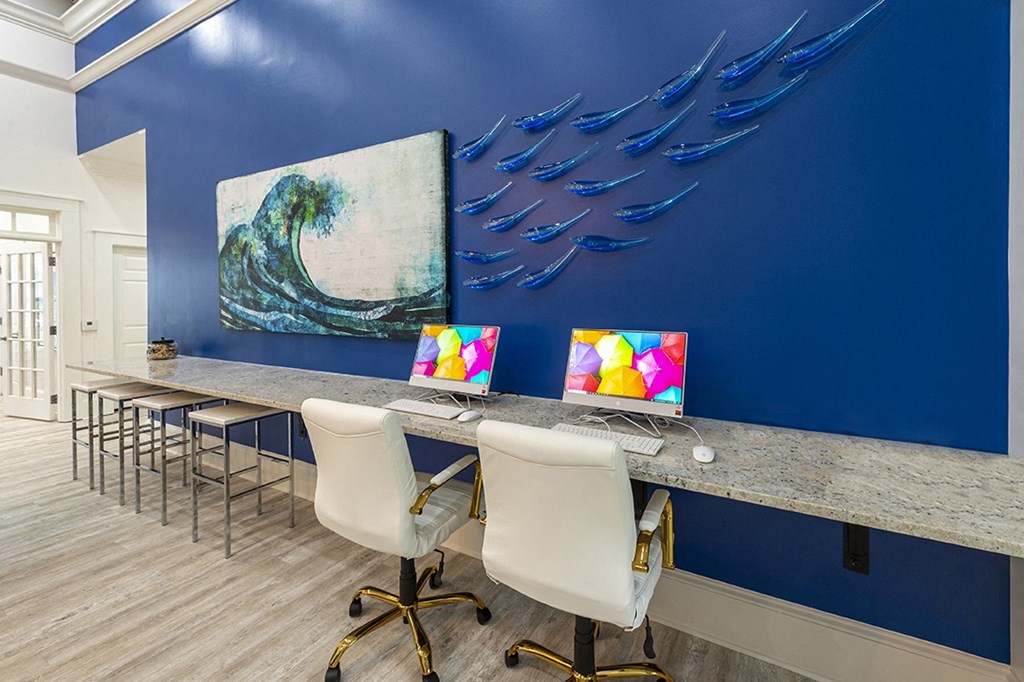 a long desk with laptops and chairs and a blue wall with a mural of birds