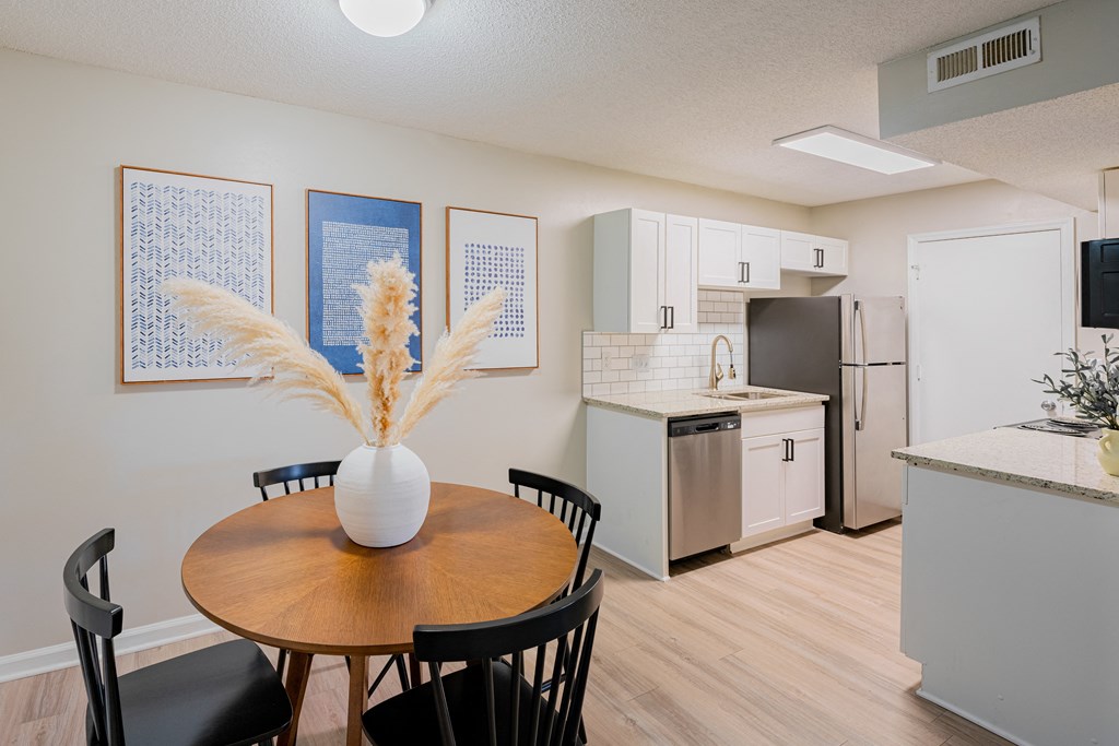 a dining room with a table and chairs and a kitchen with a refrigerator