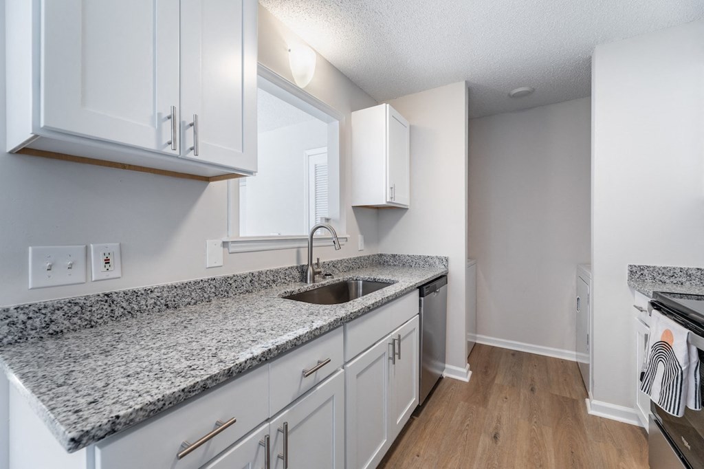 A kitchen with granite countertops and white cabinets.