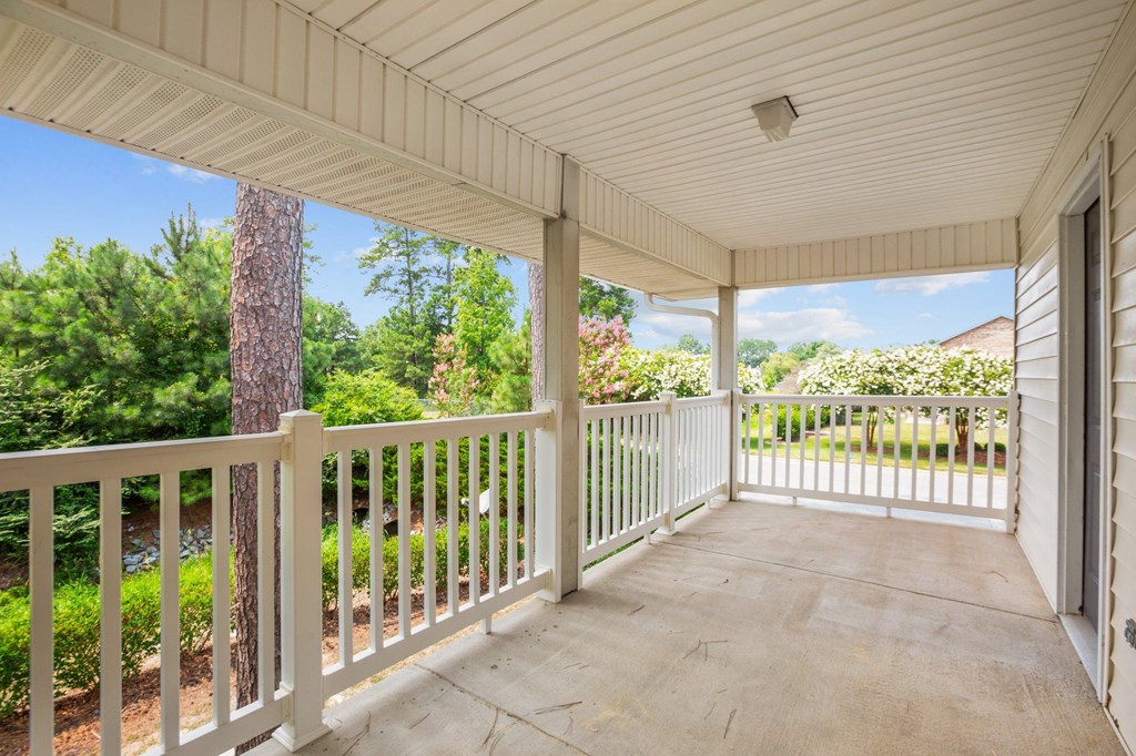 a covered porch with a view of a yard and trees
