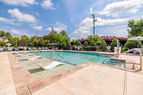 A large outdoor swimming pool with a sun lounger.