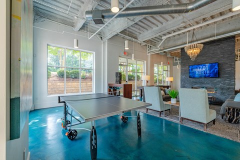 A conference room with a table and chairs and a TV screen on the wall.